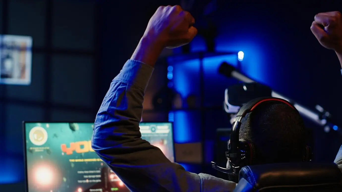 Радостный геймер поднимает кулаки в воздух от восторга после победы в игре SF.